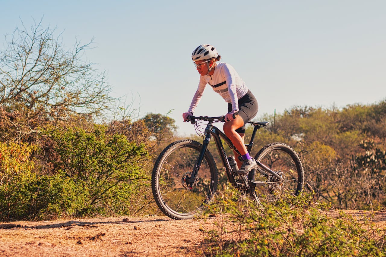 A woman mountain biking on a sunny day in the Mexican outdoors, surrounded by nature.