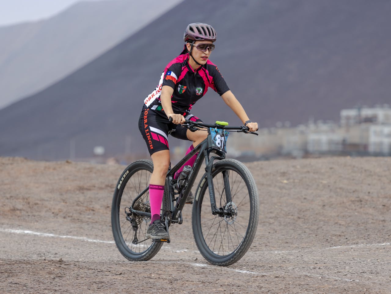 Female cyclist mountain biking on a rugged outdoor trail with scenic views.